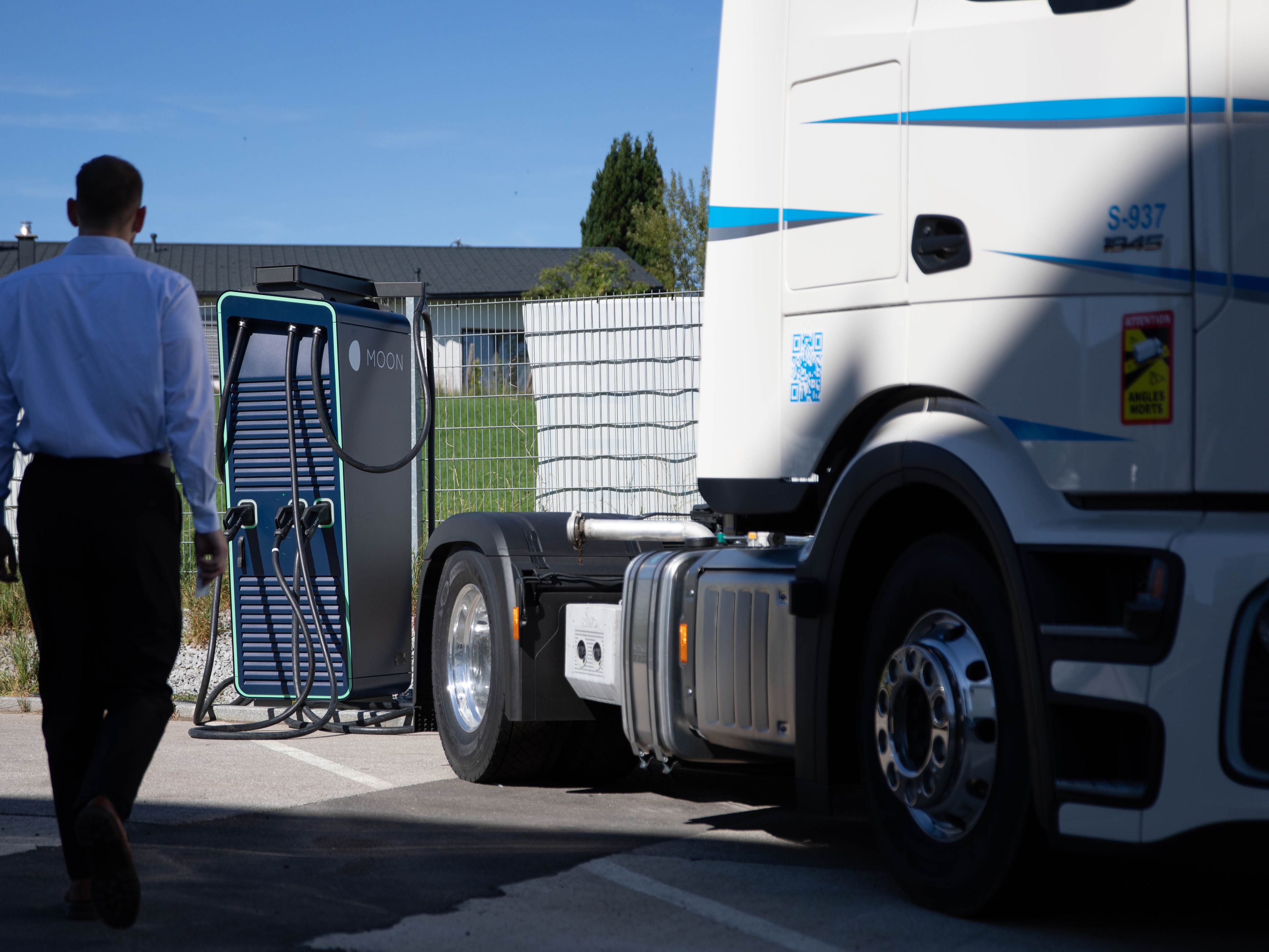 A man walks to a HYC 200-400 fast charging station next to a truck