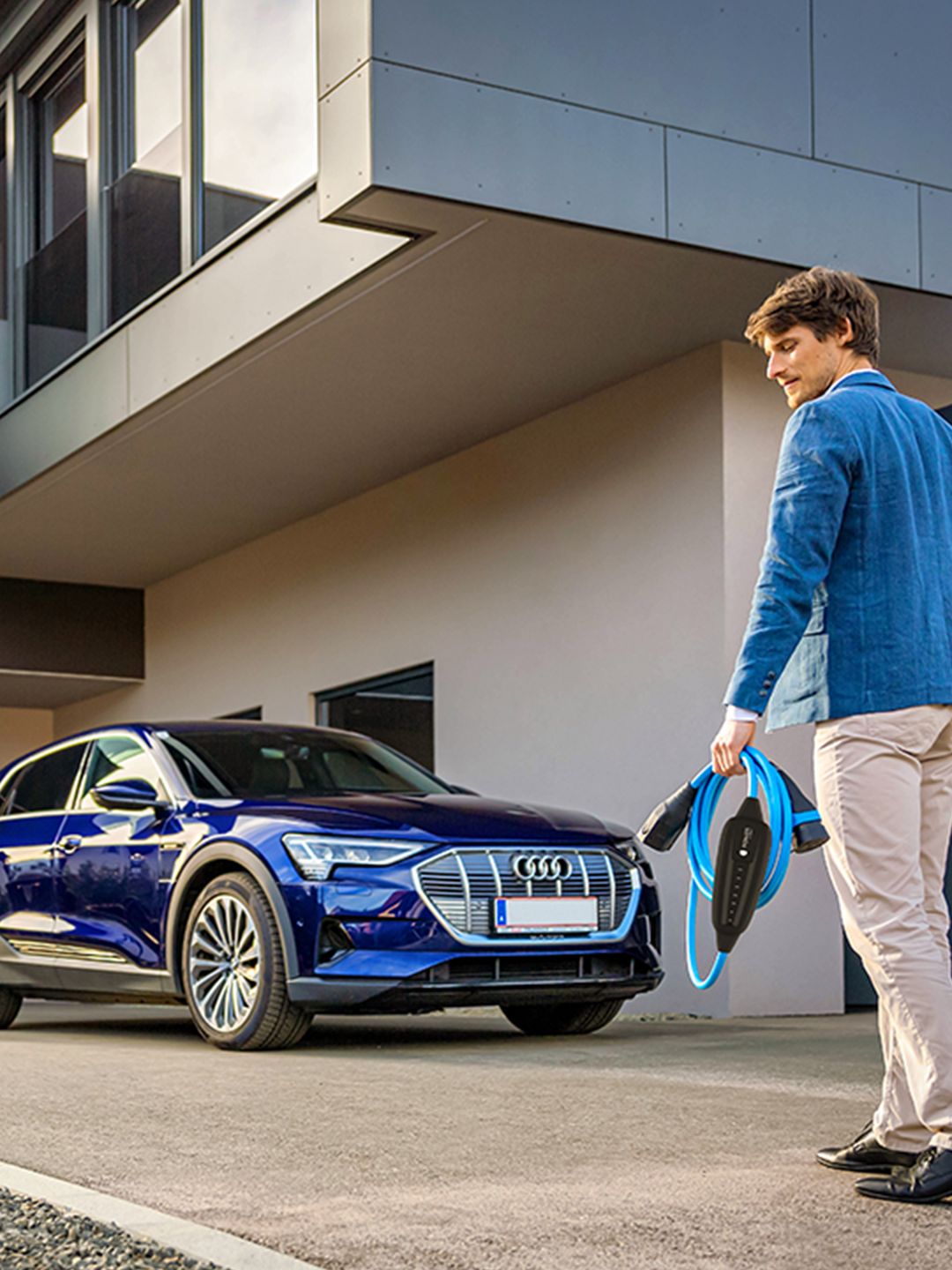 Person walks towards an electric car with cable in hand