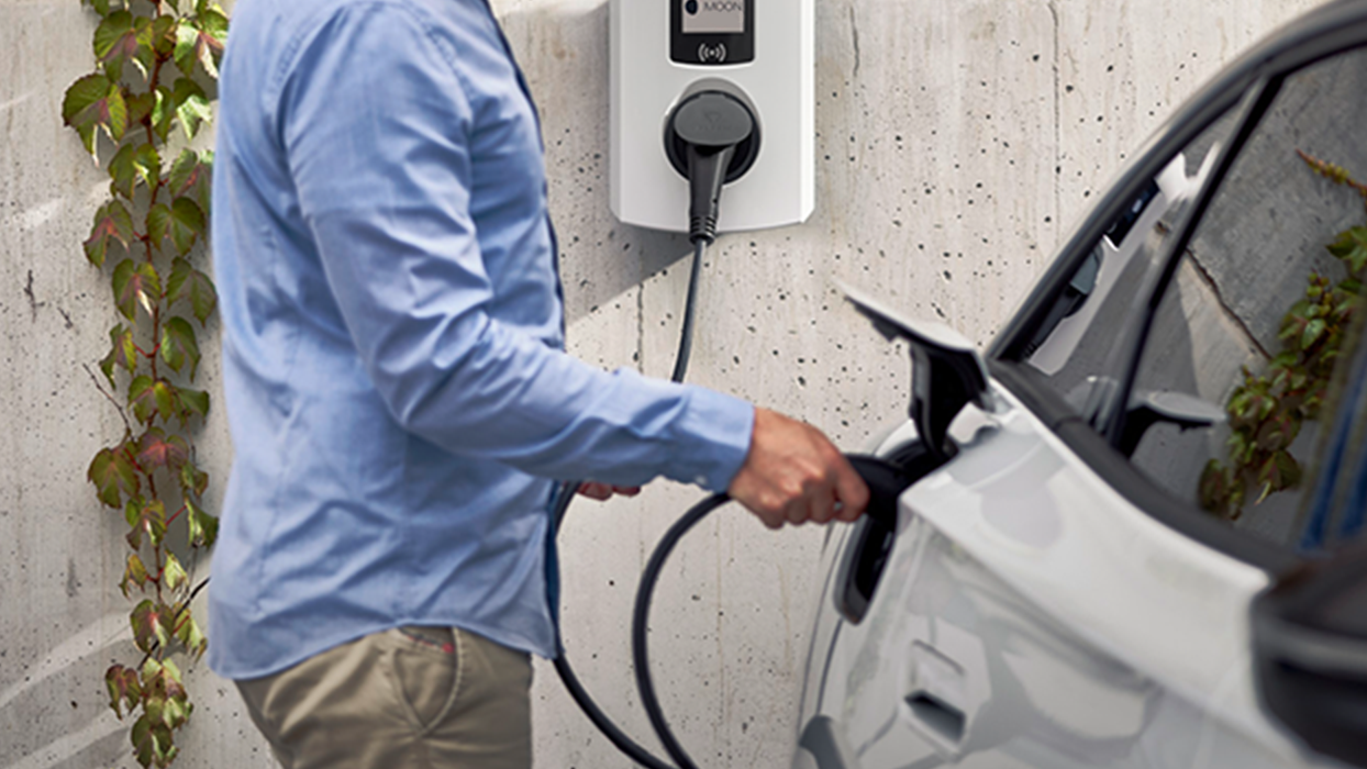 Man charging electric car with a wallbox