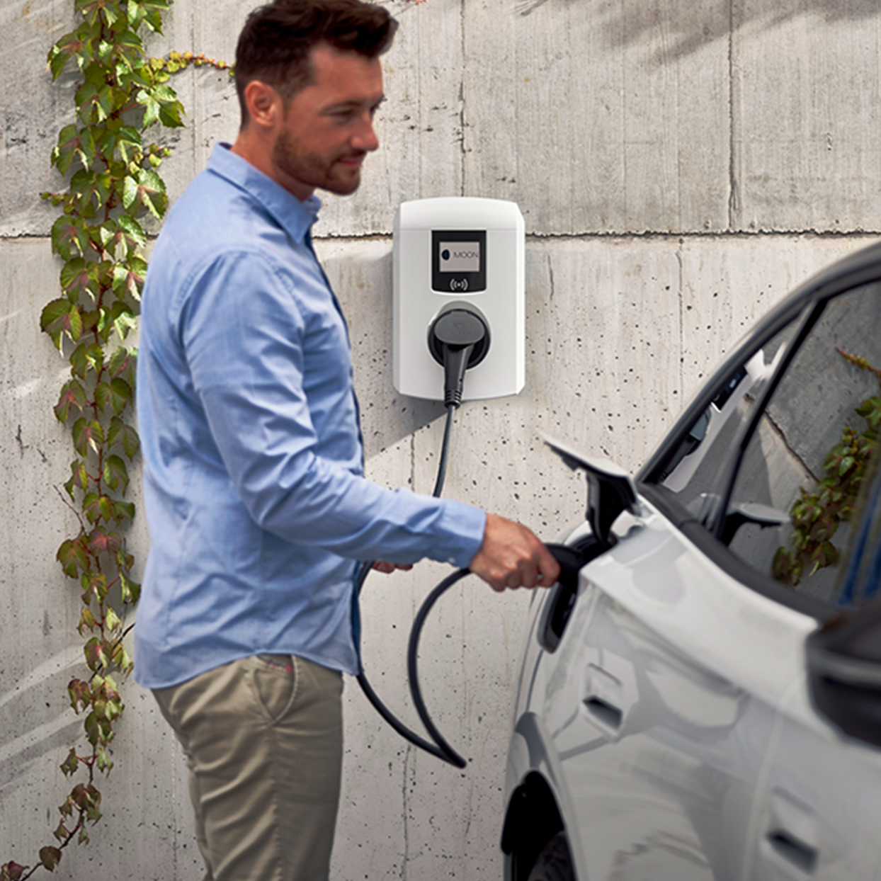 Man charging electric car with a wallbox