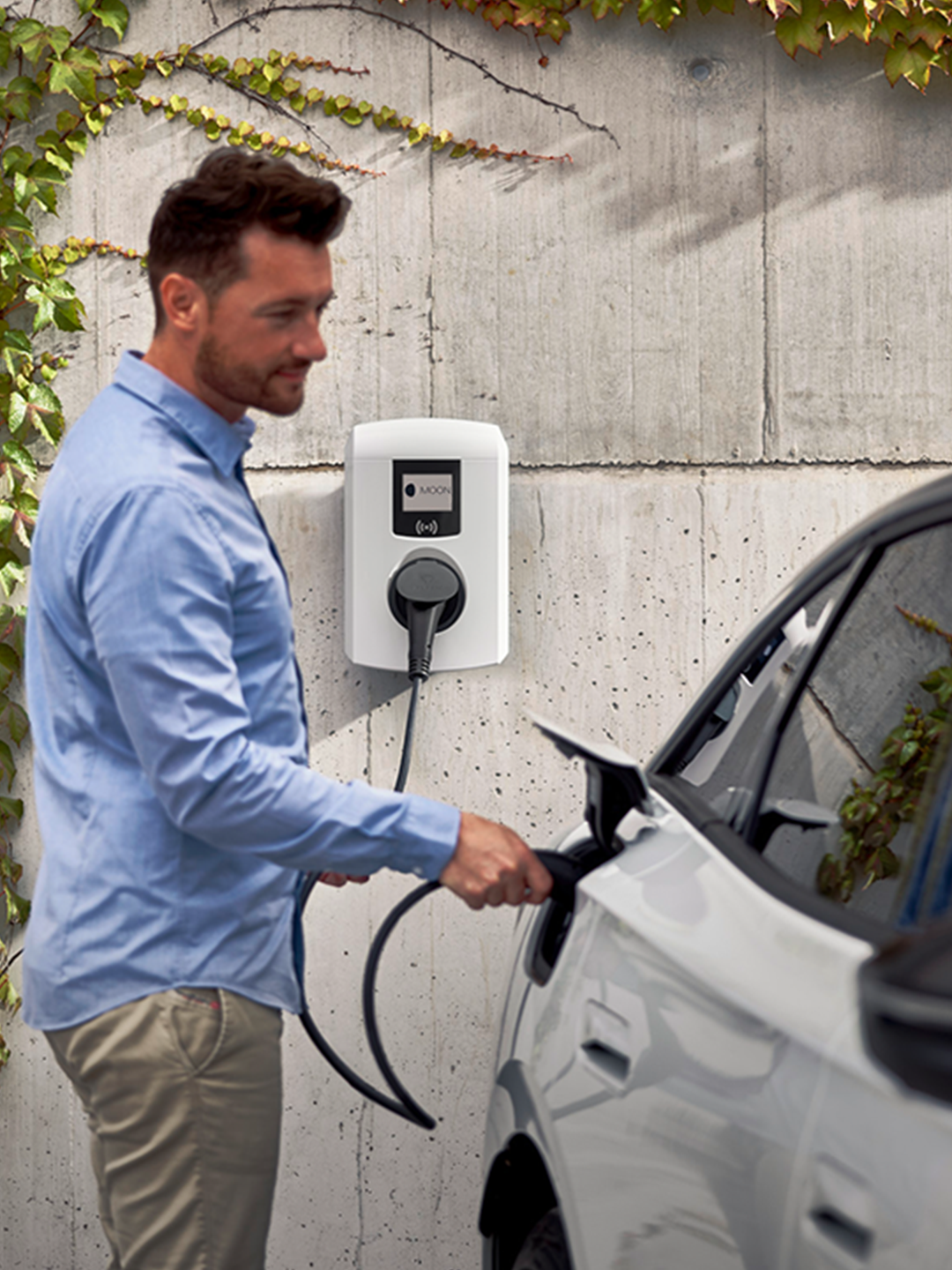 Man charging electric car with a wallbox